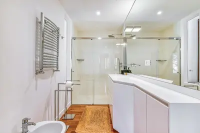 a white bathroom with a sink and a shower at Skylife Art Gallery Loft - Riverfront Art Sanctuary in Rome