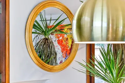 a gold mirror hanging on a wall with a plant at Skylife Art Gallery Loft - Riverfront Art Sanctuary in Rome