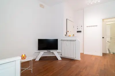 a white living room with a tv on a white table at Aurea Suite Vaticano in Rome