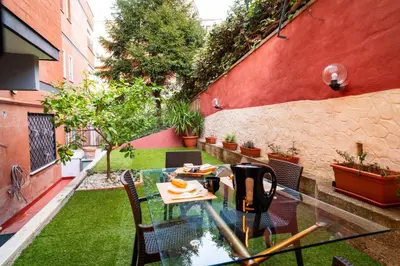 an outdoor patio with a glass table and chairs at Aurea Suite Vaticano in Rome