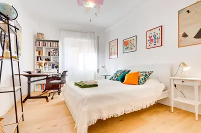 a white bedroom with a bed and a desk at Casa Ines in Rome