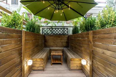 a patio with an umbrella and a table and benches at Olive Whisper Rome Garden and Sauna in Rome