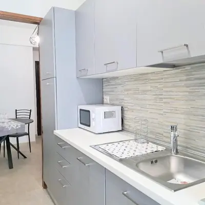 a white kitchen with a sink and a microwave at Cozy apartment near metro A in Rome