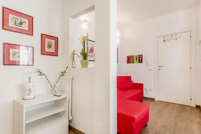 a red couch in a white room with a red chair at True Colors Vatican Home in Rome