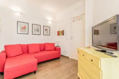 a living room with a red couch and a flat screen tv at True Colors Vatican Home in Rome