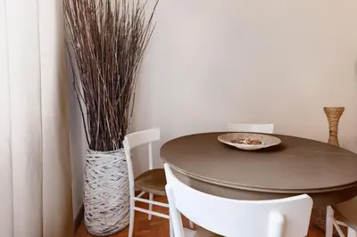 a dining room table with chairs and a vase with grass at Spanish Steps Historic Apartment in Rome