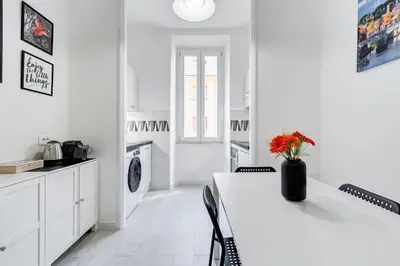 a white kitchen with a white table and chairs at Dimora Testaccio in Rome