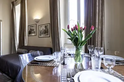 a dining room table with a vase of flowers on it at Piazza della Maddalena view in Rome