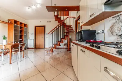 a kitchen with white cabinets and a table and a staircase at La Terrazza sul Parco Appartamento per famiglie, Vaticano, Metro A in Rome