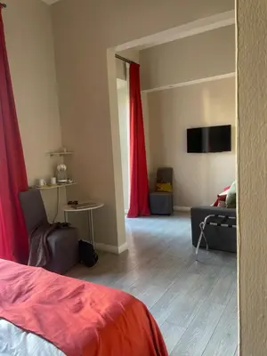 a room with a bed and a couch and red curtains at The Roman Empire Guesthouse in Rome