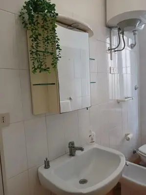 a white bathroom with a sink and a mirror at Monolocale vicino metro Libia in Rome