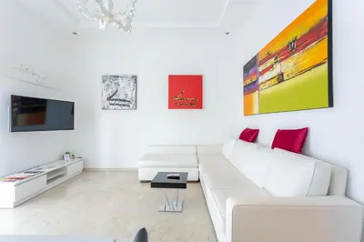 a white living room with a white couch and red pillows at Elegante Appartamento Vaticano Lattanzio in Rome