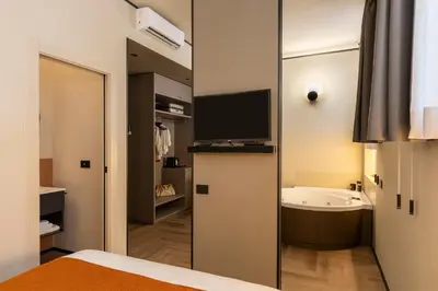 a bedroom with a bathroom with a tub and a television at San Giovanni Luxury Rooms in Rome