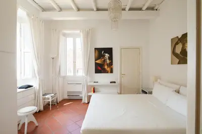 a white bedroom with a bed and a chair at Casa Mandes Spanish Steps in Rome