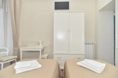 a white room with two beds and a cabinet at Romebest in Rome