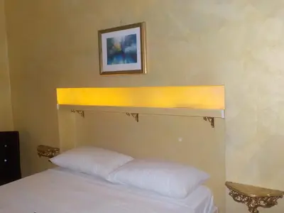 a bed with a yellow headboard and a picture on the wall at B&B Roma Royal Residence in Rome
