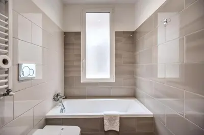 a white bathroom with a tub and a window at Homely - spacious Apt in gianicolo district in Rome