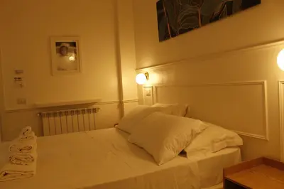 a bedroom with a white bed with two pillows at Don Raffaele Resort Roma - Guest House in Trastevere