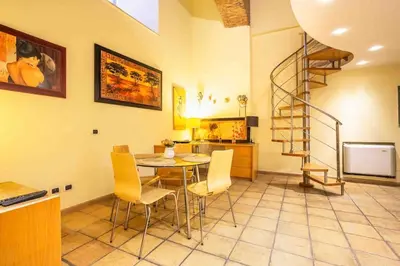 a dining room with a table and a spiral staircase at Il Nido -Cinema HD & Relax Space in Rome