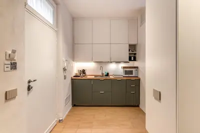 a kitchen with white cabinets and a green island at Domus Romano Piazza Farnese in Rome