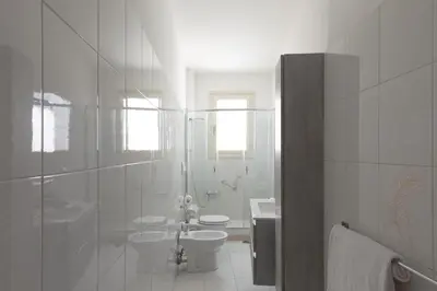 a white bathroom with a toilet and a sink at Luminoso a due passi da Trastevere in Rome