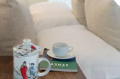 a table with a cup and a book and a coffee mug at NEW! Design apartment 2 min from Spanish Steps in Rome