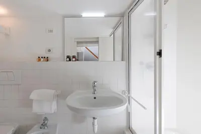 a white bathroom with a sink and a shower at Manara flats in the Heart of Trastevere in Rome