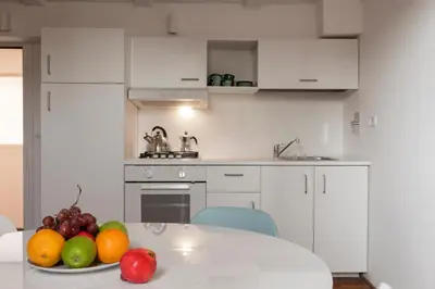 a white kitchen with a plate of fruit on a table at Manara flats in the Heart of Trastevere in Rome