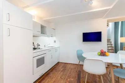 a kitchen with white cabinets and a white table and chairs at Manara flats in the Heart of Trastevere in Rome