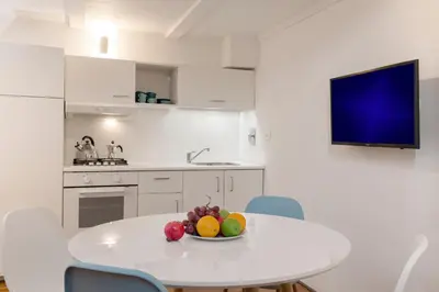 a white kitchen with a table with a bowl of fruit on it at Manara flats in the Heart of Trastevere in Rome