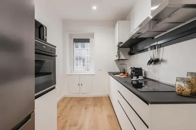a kitchen with white cabinets and black appliances at The Best Rent - Spacious three-bedroom apartment in Prati area in Rome