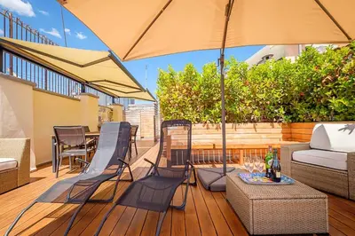 a patio with chairs and an umbrella on a deck at HT Borromini Penthouse in Rome