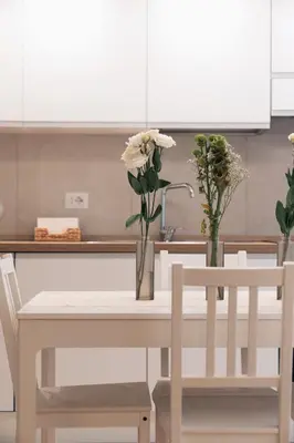 a kitchen table with two vases with flowers on it at Emma Bliss Apartment in Rome