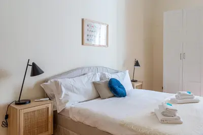 a bedroom with a bed with white sheets and blue pillows at iFlat Space and Comfort in the Heart of Monti in Rome