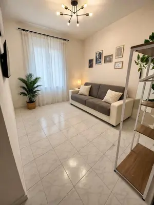 a white kitchen with a counter and stools at 2BR Flat by Metro - 6min to Colosseo - Full Kitchen - Wi-Fi - A-C in Rome