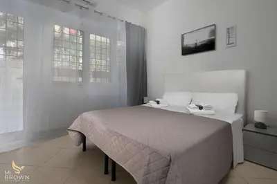 a white bedroom with a bed and two windows at Garden and Relax in Rome