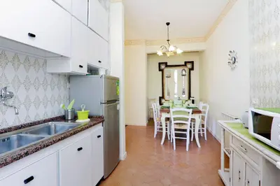 a kitchen with white cabinets and a table with chairs at Apartment Marrucini in Rome