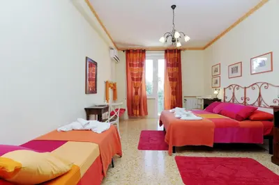 a bedroom with two beds with red and orange sheets at Apartment Marrucini in Rome