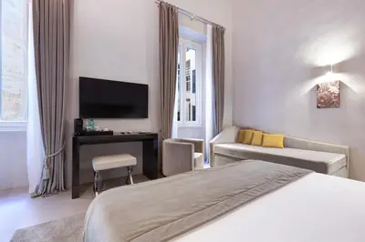 a bedroom with a bed and a desk with a television at Terrace Pantheon Relais in Rome