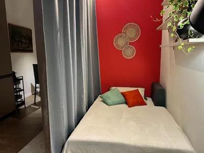 a small bed in a room with a red wall at CBMC - Couldn't Be More Central in Rome