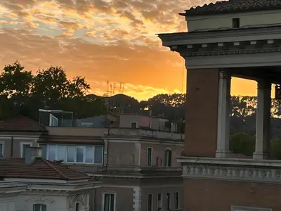 a building with a sunset in the background at CBMC - Couldn't Be More Central in Rome