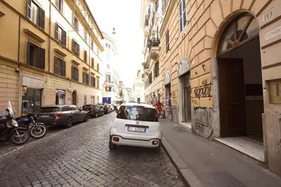 a small white car parked on a street with buildings at Manara Holiday House in Rome