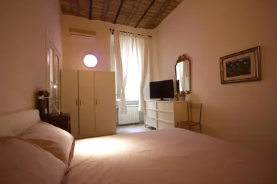 a bedroom with a white bed and a television at Manara Holiday House in Rome