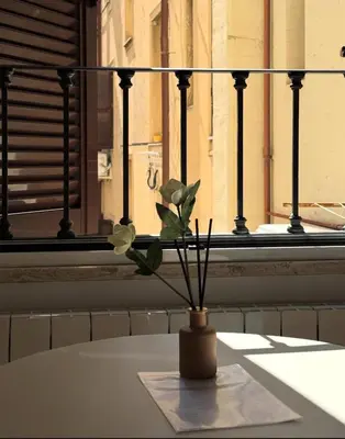 a vase with a flower on a table in front of a window at Flat 7 Rome Guesthouse in Rome