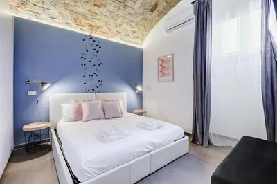 a bedroom with a white bed and a blue wall at FaMa - Le Volte in Rome