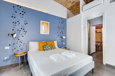 a bedroom with a white bed and a blue wall at FaMa - Le Volte in Rome