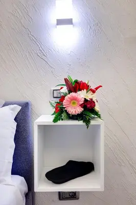 a white shelf with a bouquet of flowers on it at V Collection Rome Jubilee Guest House in Rome