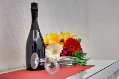 a bottle of wine sitting next to a bouquet of flowers at V Collection Rome Jubilee Guest House in Rome