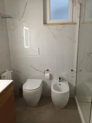 a white bathroom with a toilet and a sink at Casa Erminia in Rome