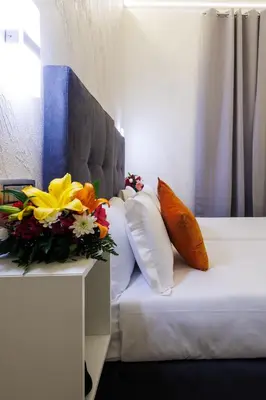 a bed with a bouquet of flowers on a table at V Collection Vatican Jubilee Guest House in Rome